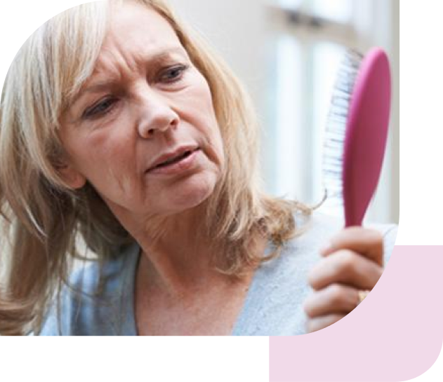 Eine Frau mit blonden Haaren schaut besorgt auf eine pinke Haarbürste