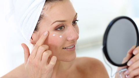 Eine Frau cremt sich nach dem Duschen das Gesicht ein