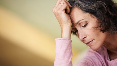 Eine Frau stützt sich mit ihrer Hand den Kopf als ein Zeichen von Stimmungsschwankungen